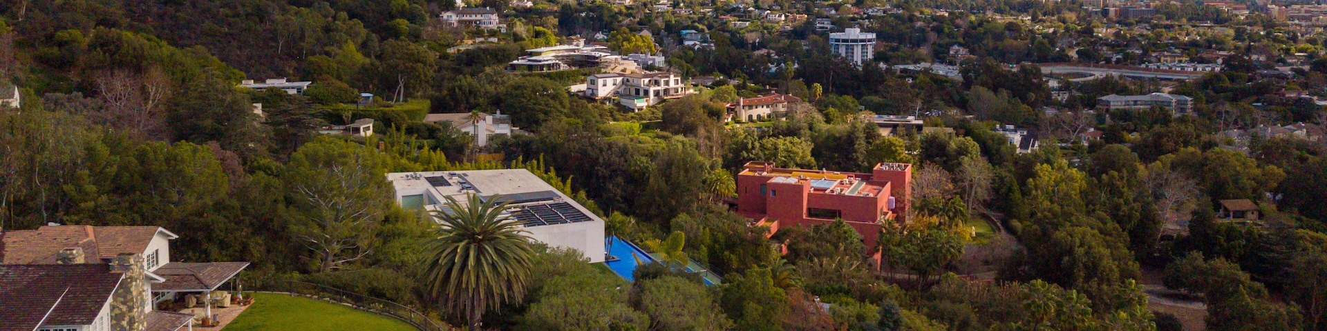 Zona residencial con piscina, casas y un horizonte urbano lejano.