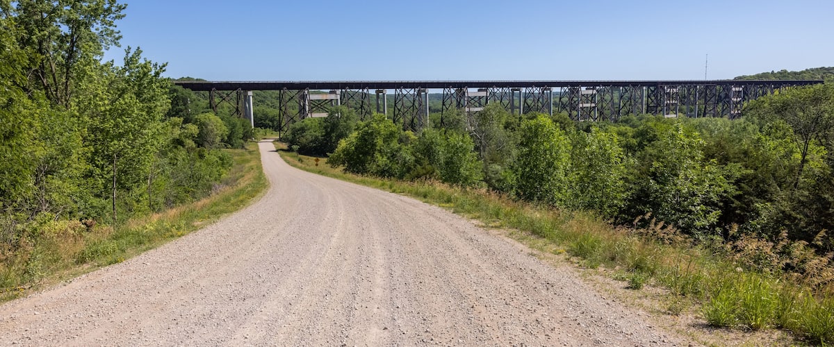 A gravel road leading to a bridge over a river.
