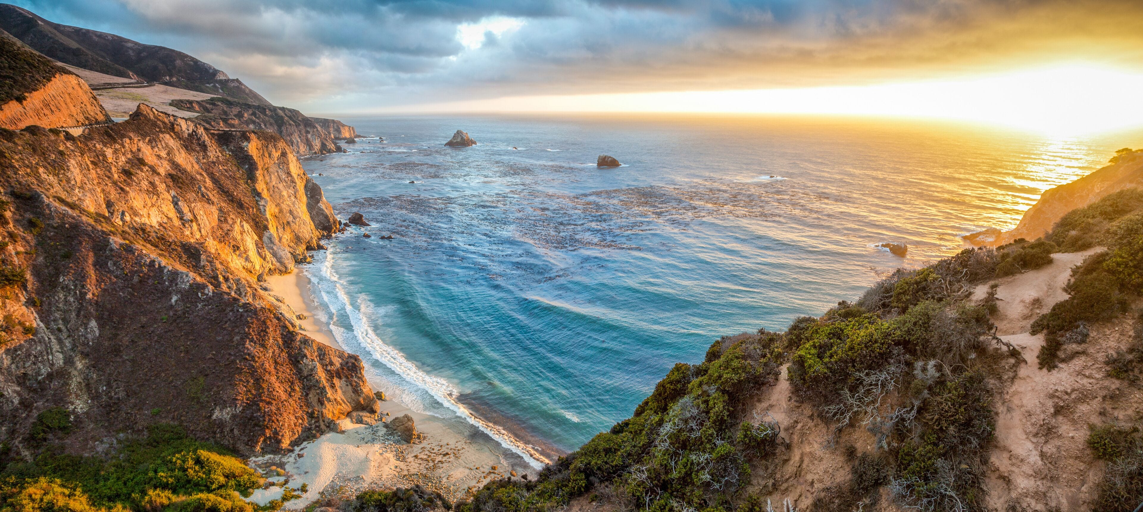 A coastal landscape with cliffs, a beach, and the ocean.