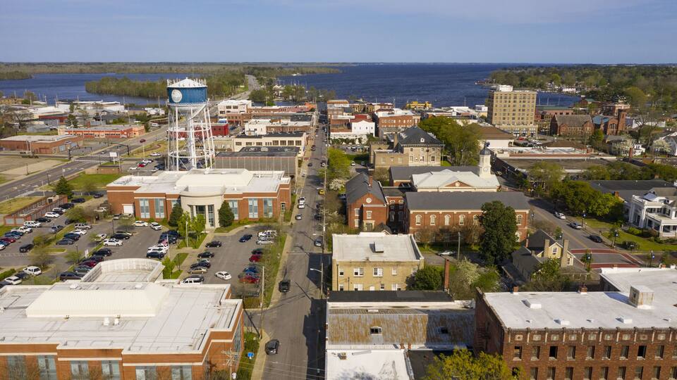 A coastal town with a prominent water tower, historic buildings, and a marina.