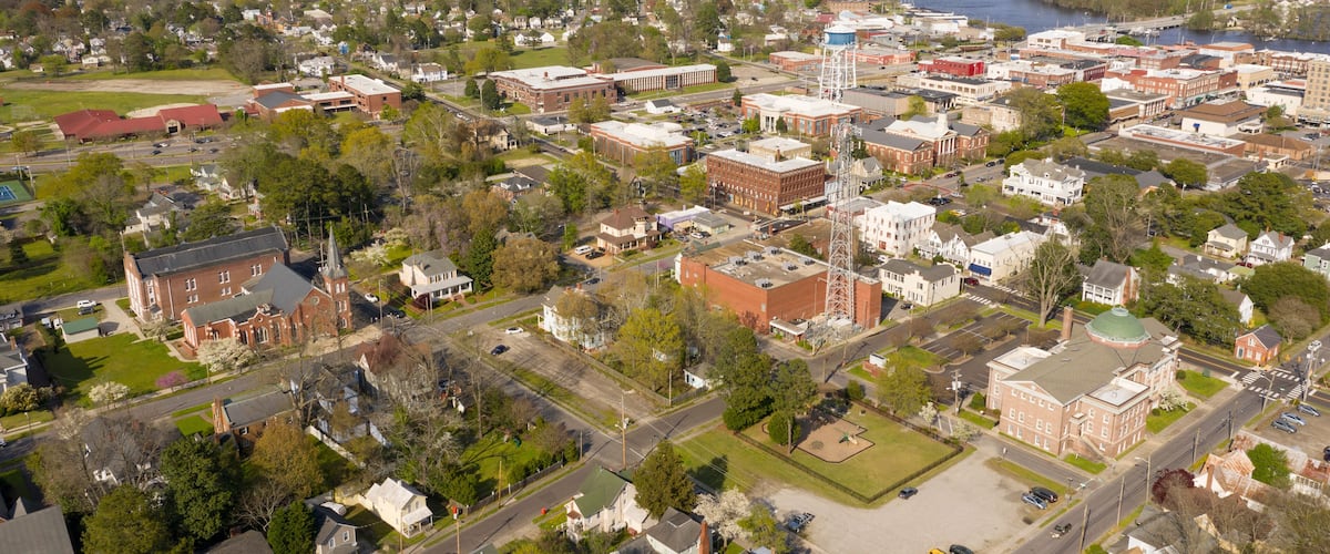 An aerial view of a town with a river, buildings, and a church.