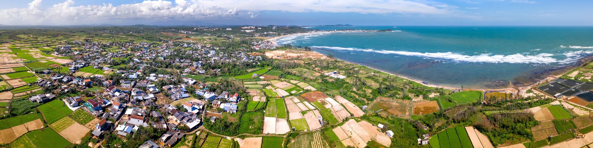 A coastal town with fields, houses, and a beach.