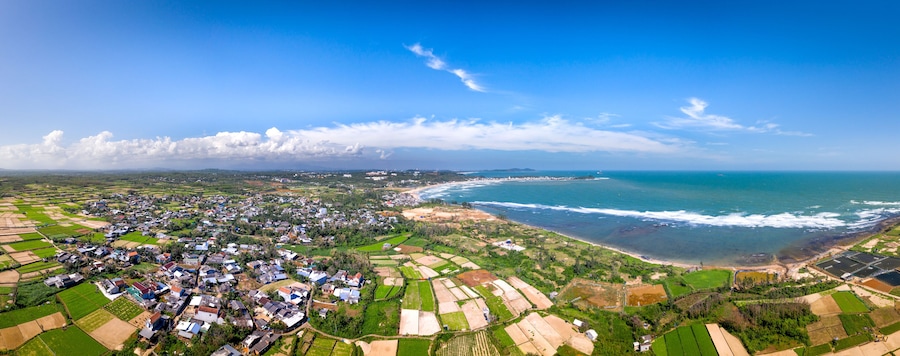 A coastal town with fields, houses, and a beach.