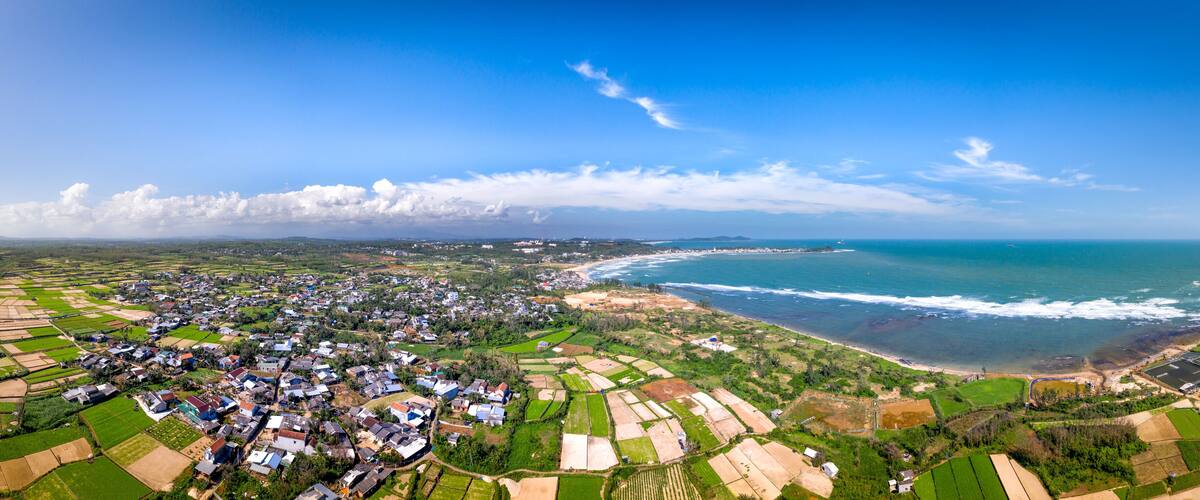 A coastal town with fields, houses, and a beach.