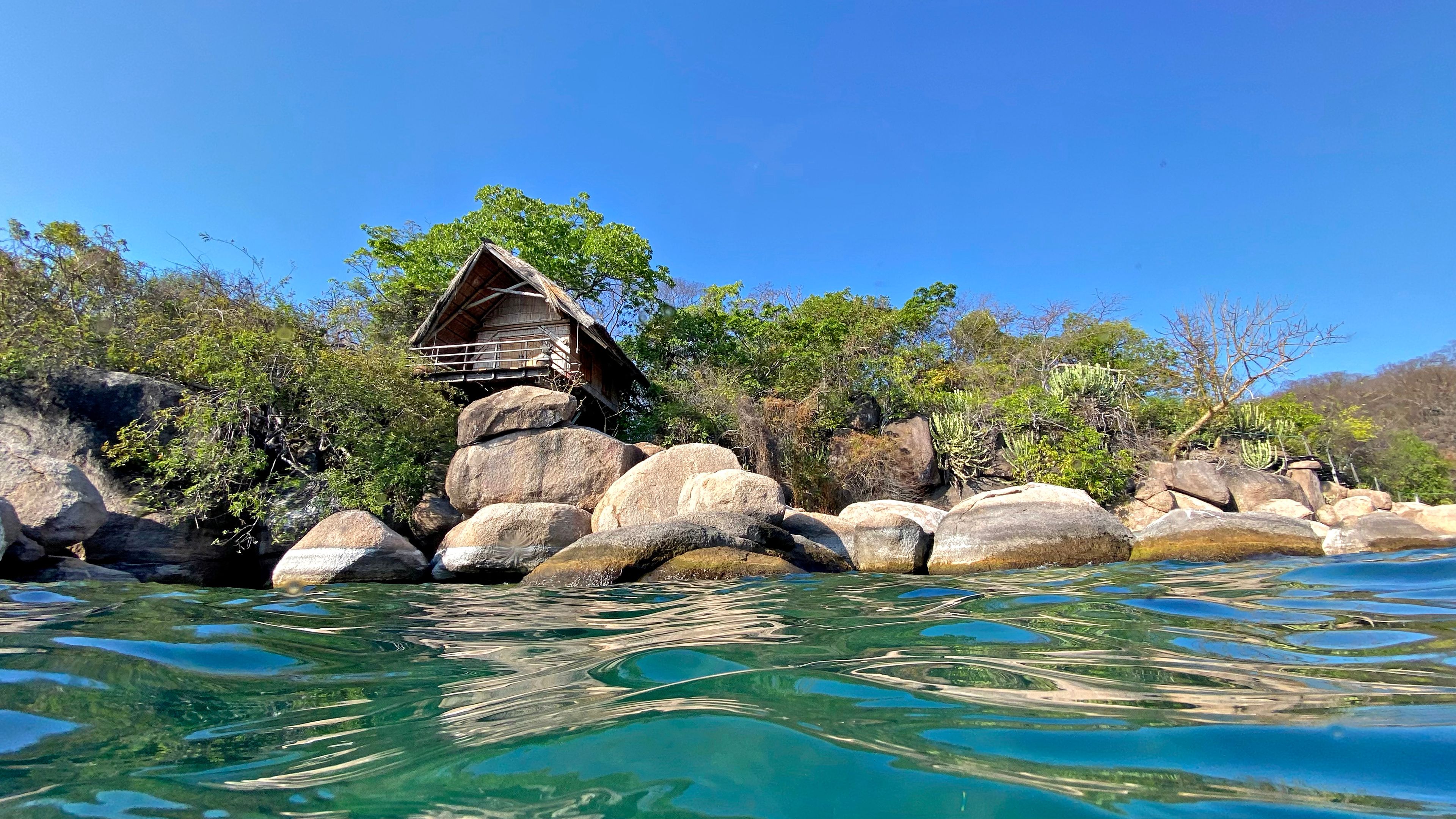 A unique water view of quaint, rustic holiday chalets or huts on the beautiful island resort on Mumbo Island in Lake Malawi.