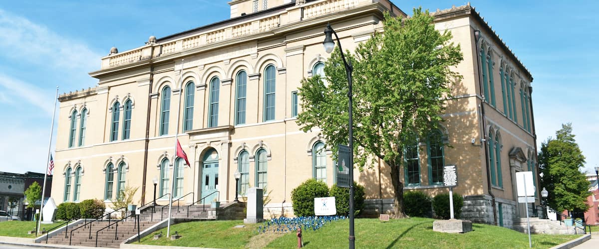 A historic building with a clock tower, arched windows, and a flag.