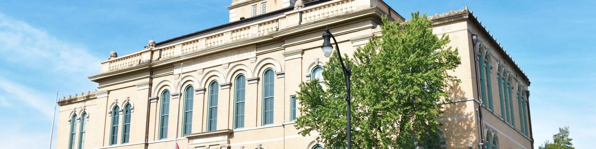 A historic building with a clock tower, arched windows, and a flag.