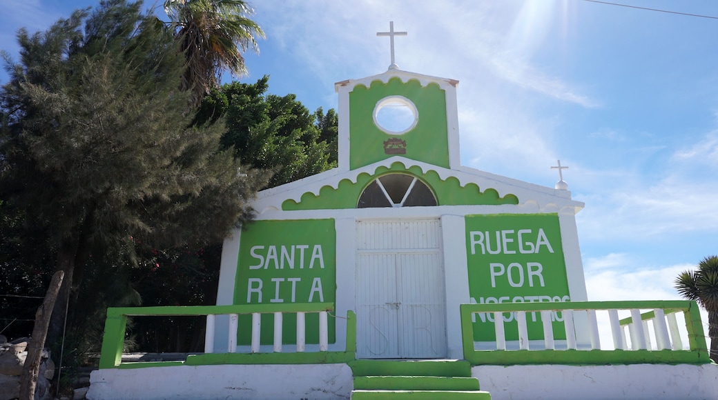 A small church with a green and white facade, a cross on top, and the words 'Santa Rita' and 'RUEGA POR NOSTROS' on the sides.
