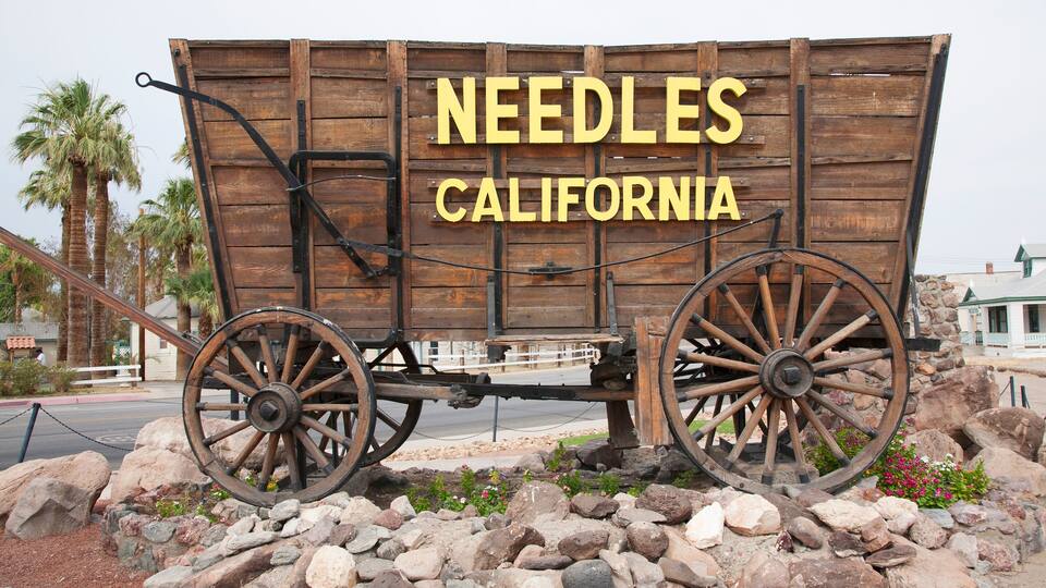 A wooden sign with 'NEEDLES CALIFORNIA' and a vintage wagon wheel.