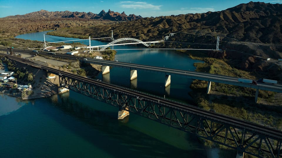 A bridge over a river with mountains in the background.