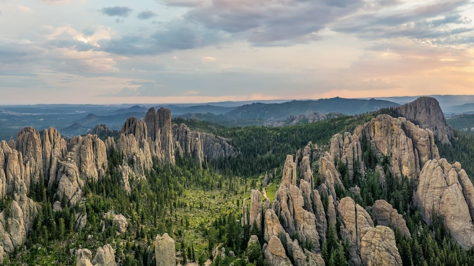 A mountainous landscape with prominent rock formations and dense forest.
