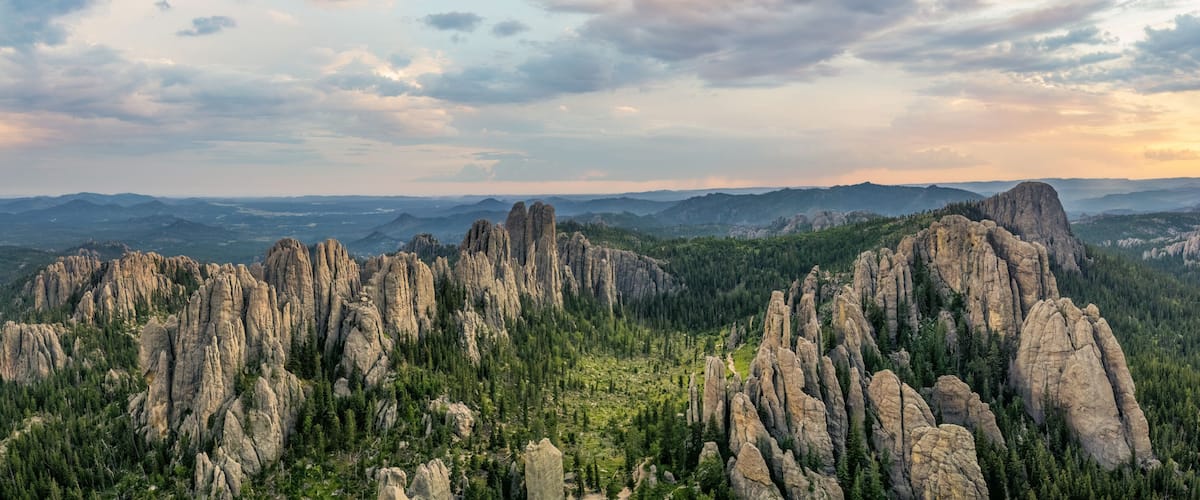 A mountainous landscape with prominent rock formations and dense forest.