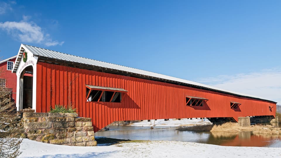 A red covered bridge over a frozen river.