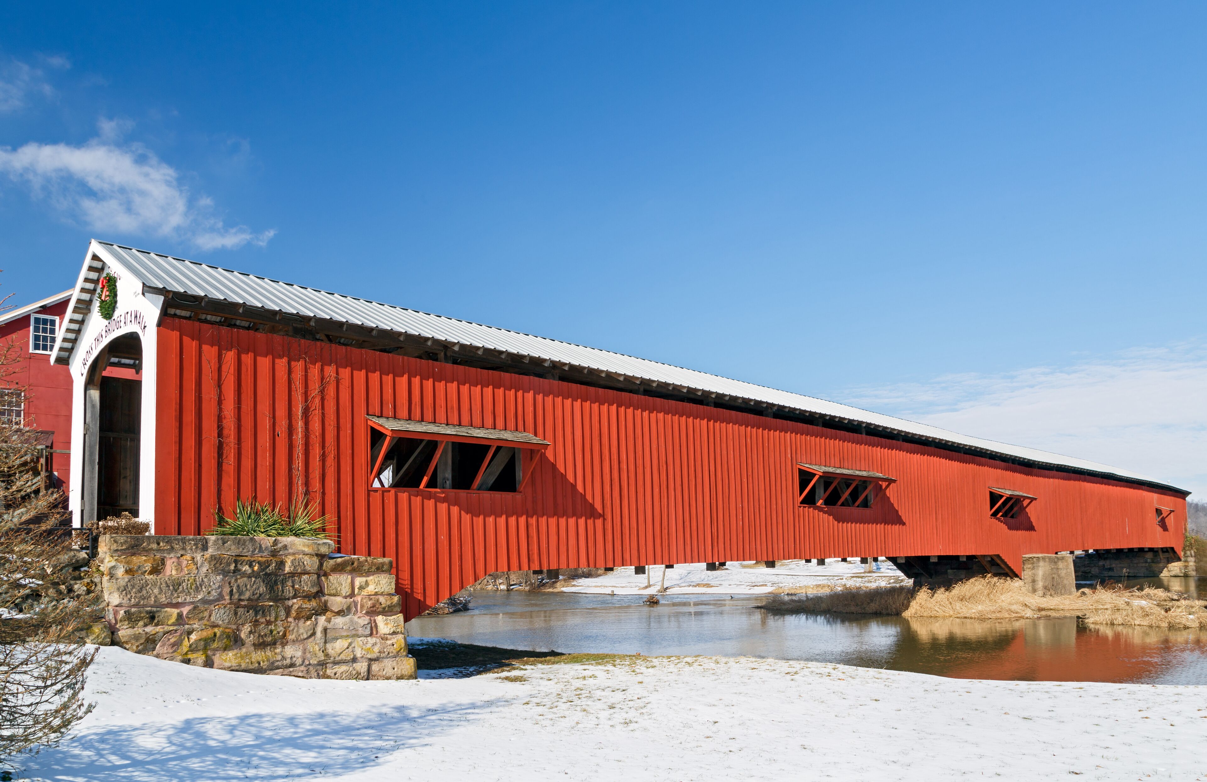 A red covered bridge over a frozen river.
