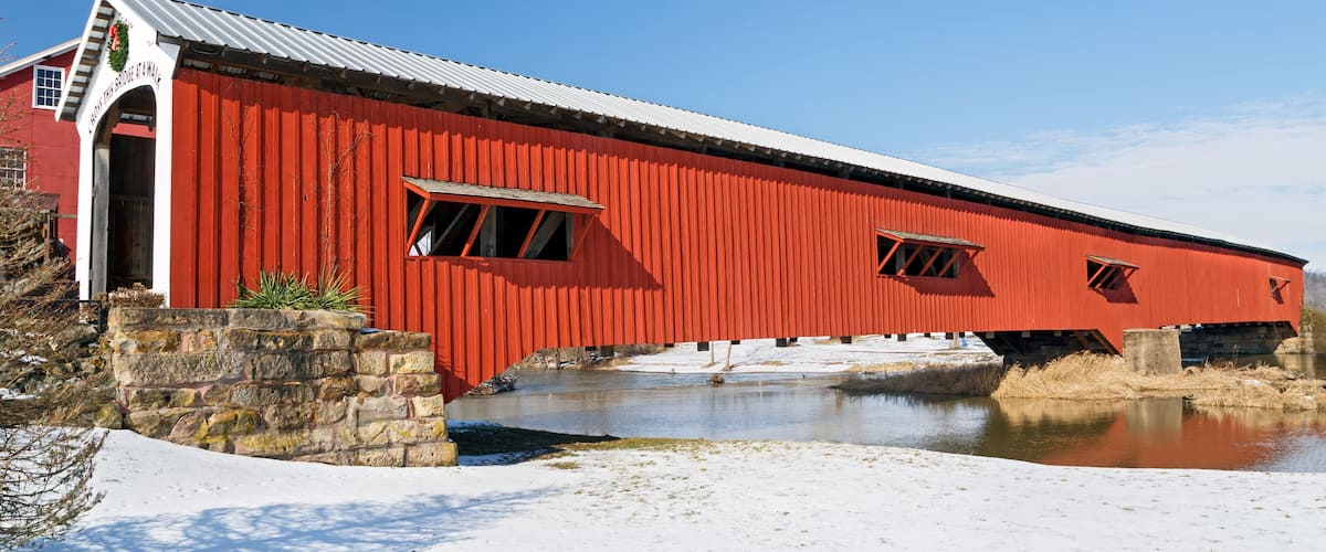 A red covered bridge over a frozen river.