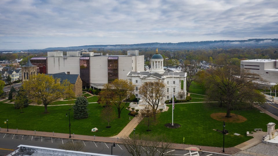 A large white building with a dome, surrounded by green lawns and trees.