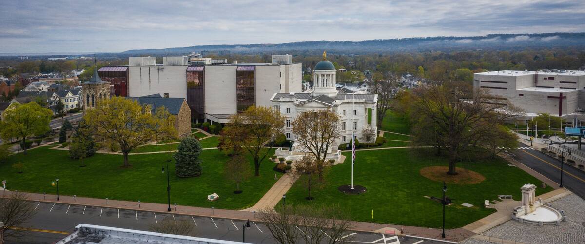 A large white building with a dome, surrounded by green lawns and trees.