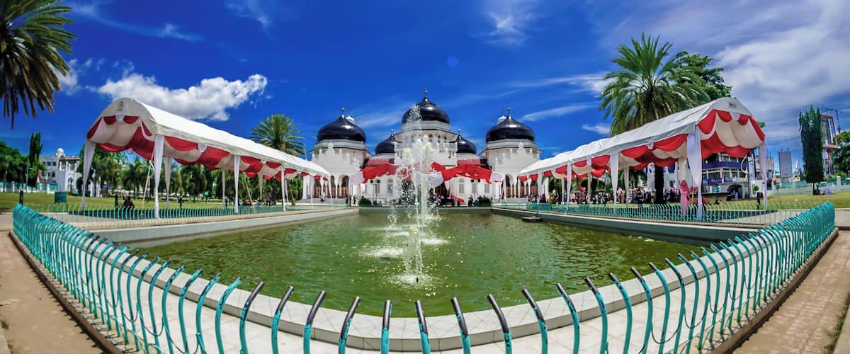 Baiturrahman Grand Mosque
The original Masjid Raya ("Grand Mosque") was built in 1612 during the reign of Iskandar Muda, Sultan of Aceh. Some say the original mosque was built even earlier in 1292 by Sultan Alaidin Mahmudsyah. The original royal mosque features a multi-tiered thatched roof, a typicalAcehnese architecture.
During the First Aceh Expedition, the mosque became a center of armed resistance to the Dutch and therefore it was destroyed razed to the ground on 6 Januari 1874 by the East Indies Governor General van Swieten. In March 1877, the Dutch offered to rebuild the mosque to the local rulers. Construction only began in 1879. The first stone was laid by Tengku Qadhi Malikul Adil who became the first Imam. Construction was completed on 27 December 1881 during the rulership of Muhammad Daud Syah, the last sultan of Aceh. Initially, many Acehnese refused to pray at Baiturrahman, because it was built by the Dutch with ambitions to conquer Aceh, however today it is the pride of Banda Aceh.
At first, the Baiturrahman Mosque featured one dome and one minaret. More domes and minarets were added in 1935, 1958 and 1982. Today the mosque has seven domes and eight minarets, including one that is claimed to be the highest minaret in Banda Aceh.
Baiturrahman Grand Mosque survived the 2004 earthquake and tsunami but suffered minor damages such as wall cracks. The earthquake had slightly tilted and cracked the 35 meter minaret by the main gate. During the disaster, The mosque served as a temporary shelter for displaced persons and only reopened for prayers after two weeks.