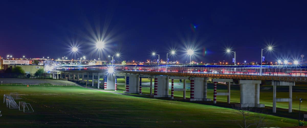 A nighttime view of a bridge with streetlights and a lit highway.