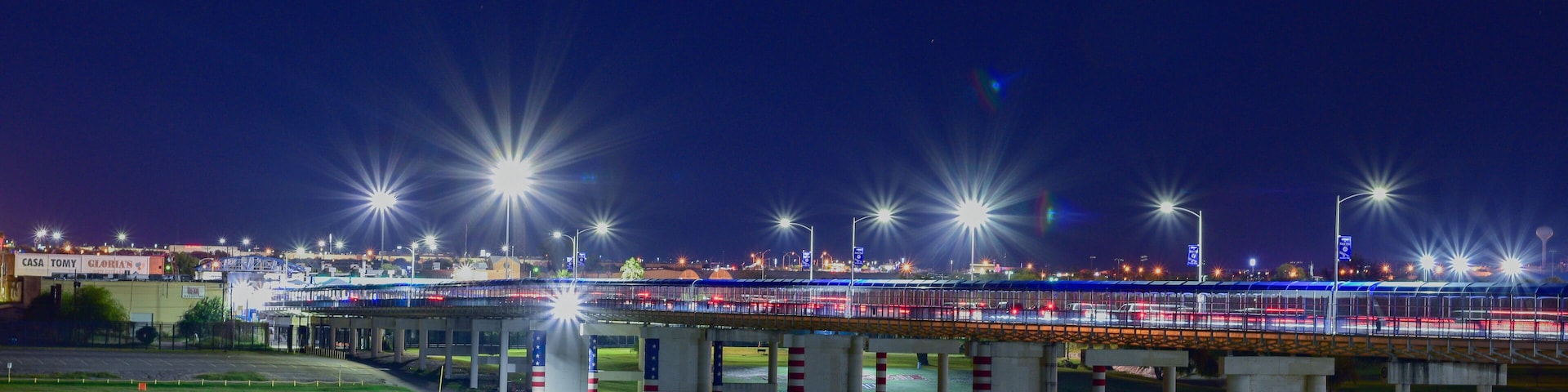 A nighttime view of a bridge with streetlights and a lit highway.
