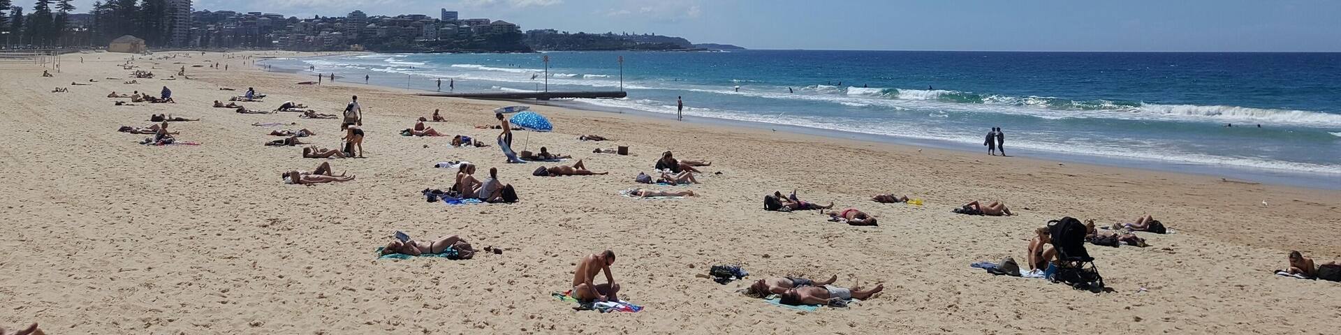 A beach with people sunbathing and swimming.