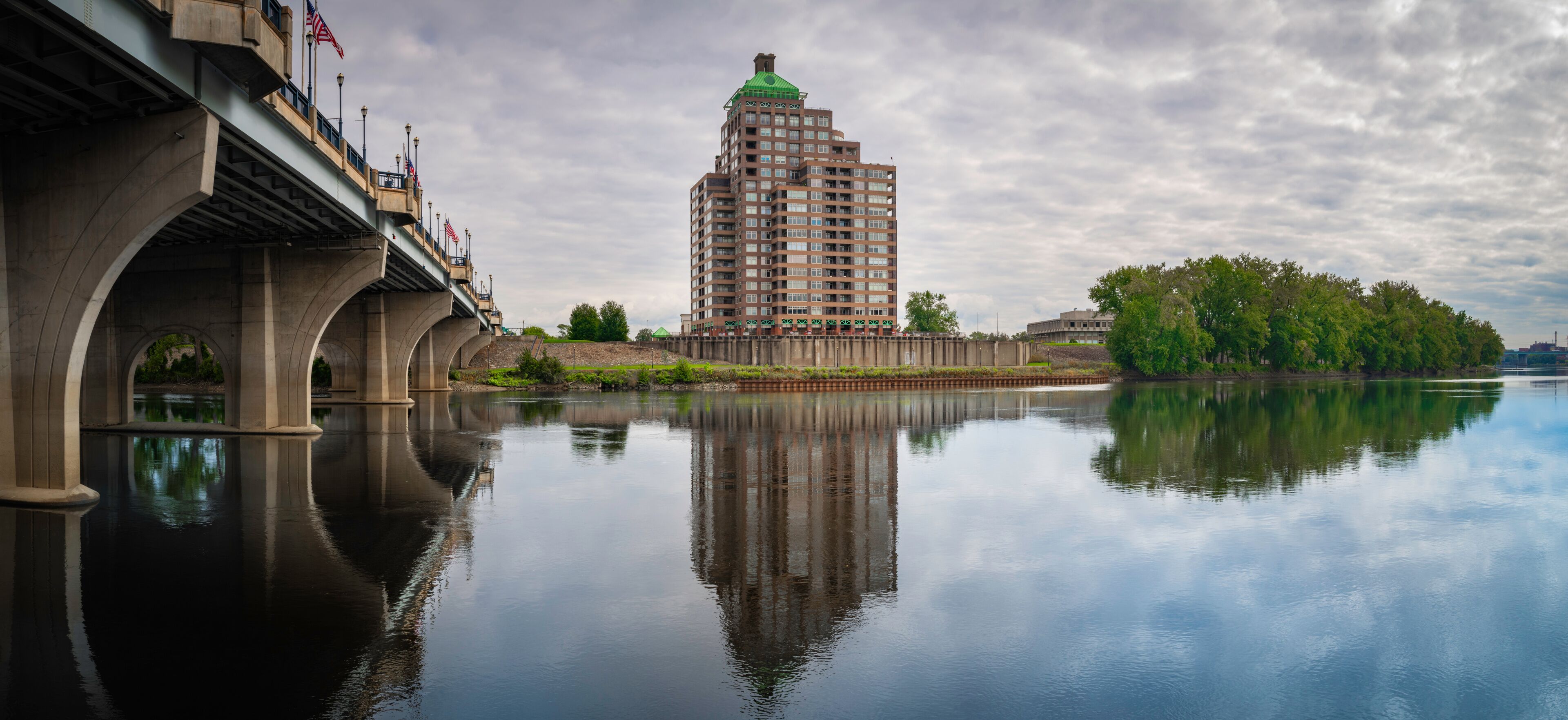 Peaceful panoramic landscape over Connecticut River with the view of Founder's Bridge and buildings and forest on the riverbank on East Hartford.