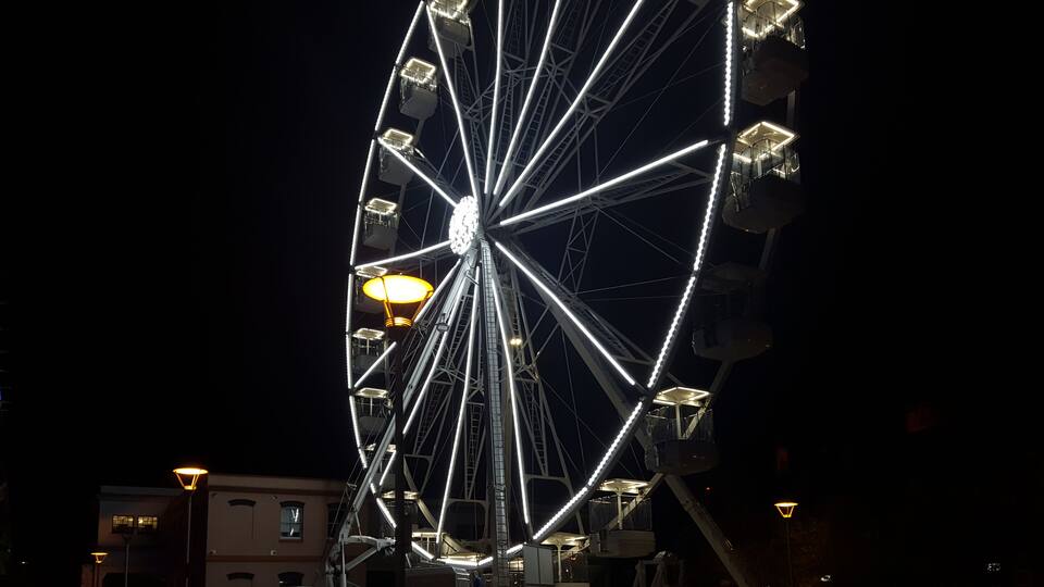 A large Ferris wheel with bright lights against a dark night sky.