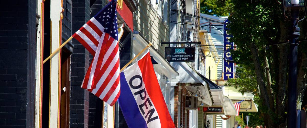 A street with flags, a sign for Exit Harborside Realty, and a Persimmon store.