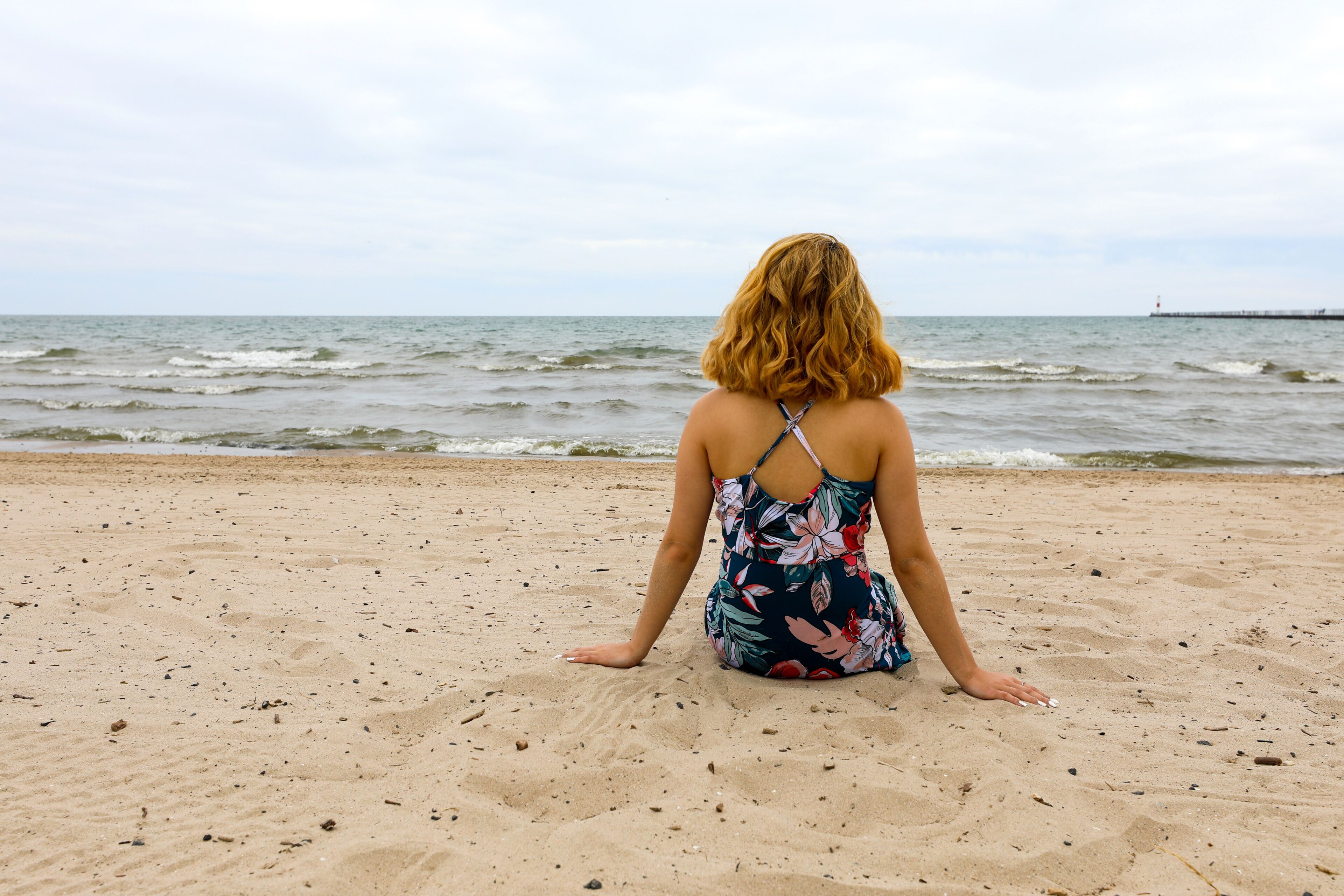 A person sitting on a sandy beach with the ocean in the background.