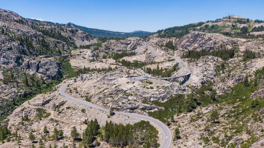 A winding mountain road surrounded by rocky terrain and sparse vegetation.