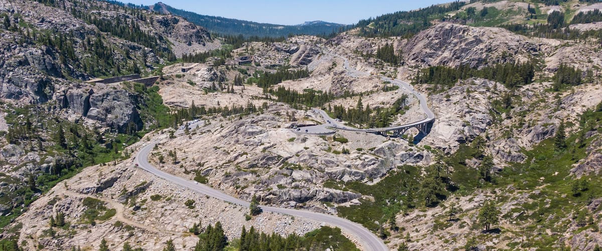 A winding mountain road surrounded by rocky terrain and sparse vegetation.