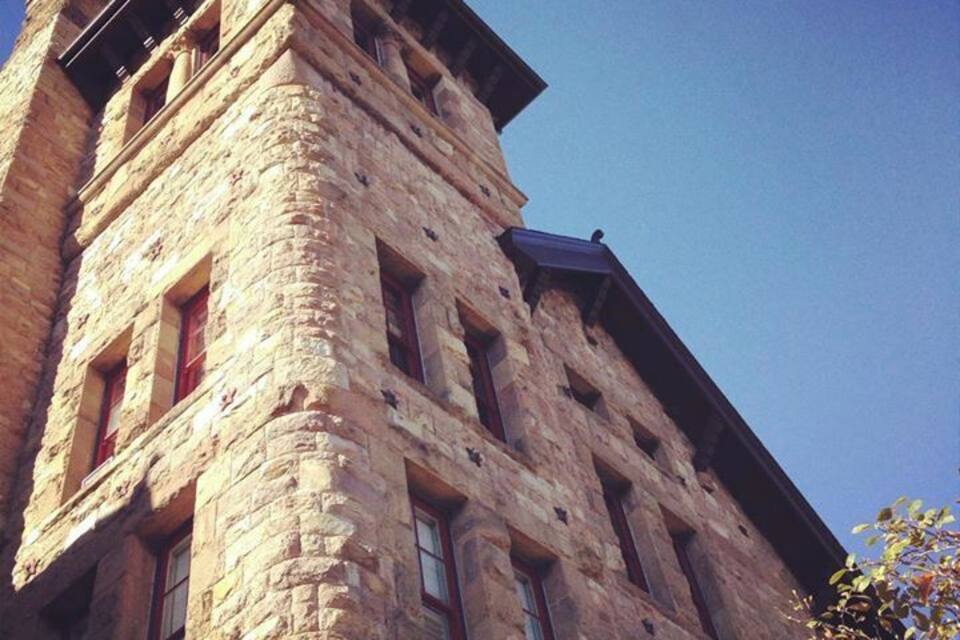 A historic stone building with multiple windows and a steeply pitched roof.