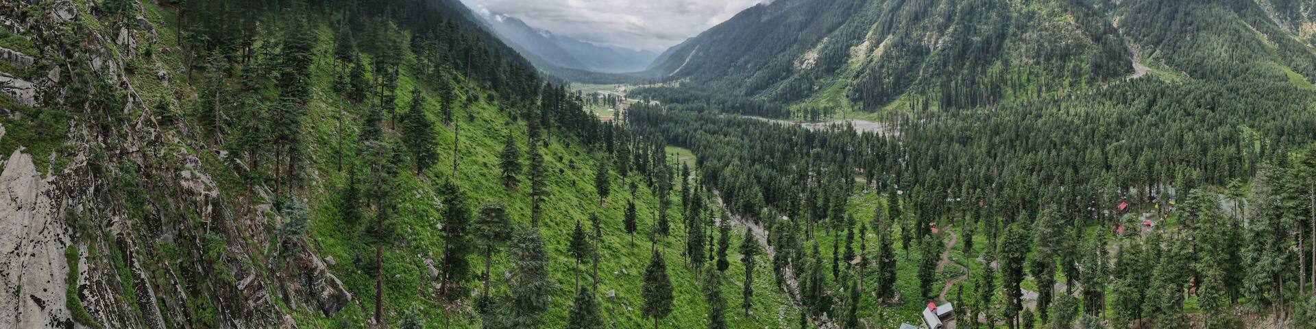 An aerial view of Kumrat Valley and its lush green forest with some clouds in the sky.