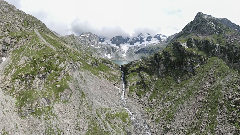 A mountainous landscape with a glacier and a small lake.