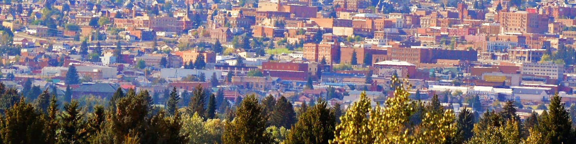 Butte showing mountains, a small town or village and a city
