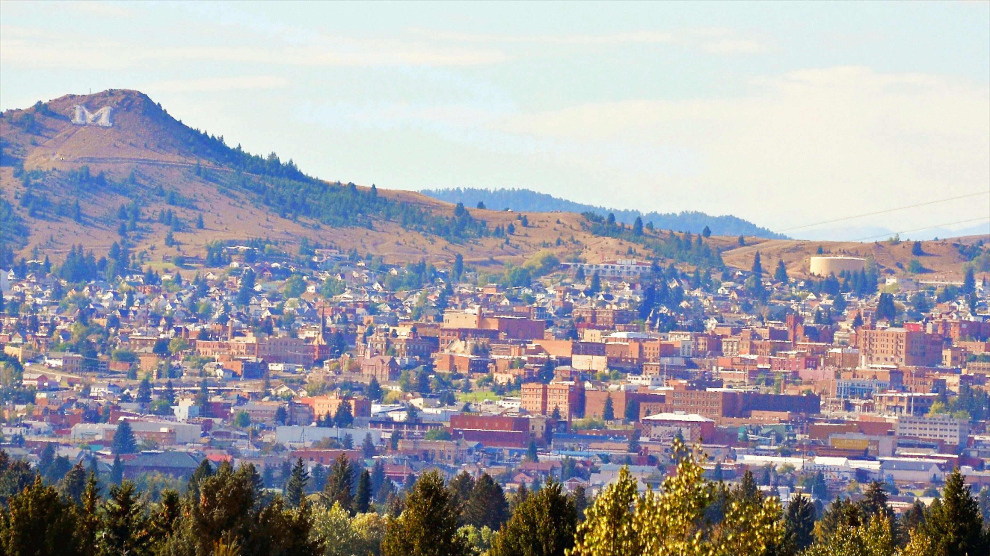 A town with a prominent hill in the background, dense residential buildings, and a mix of commercial structures.