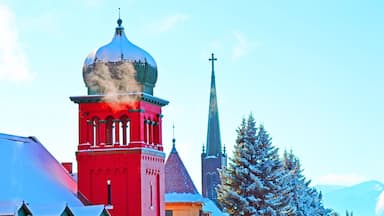 A church with a red tower and a steeple emitting smoke.