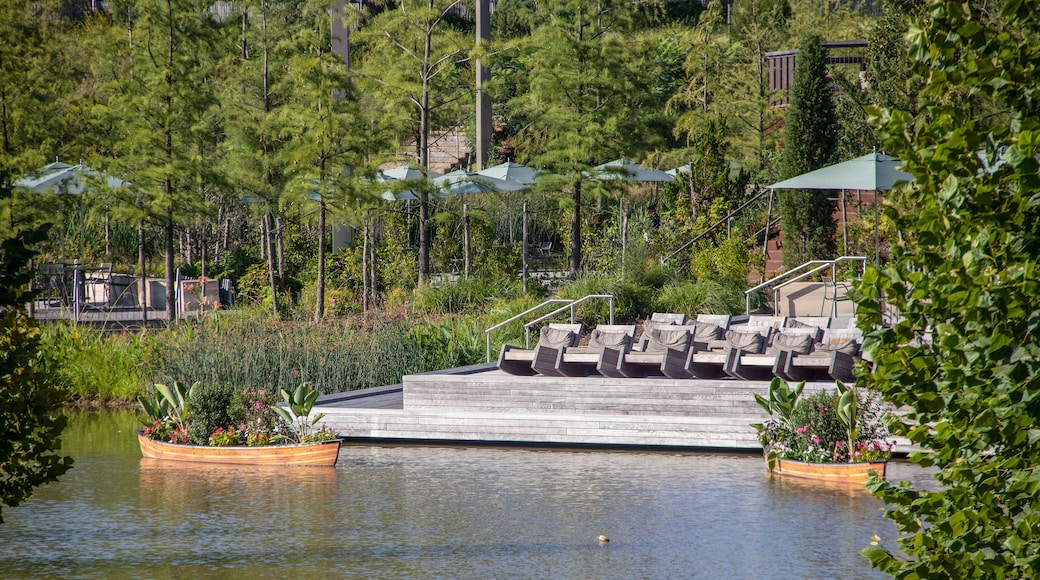 The Gathering Place - Award winning public park in Tulsa OK USA - Wooden deck with chairs beside pond with rowboats filled with flowers and tables and umbrellas and trees behind - selective focus
