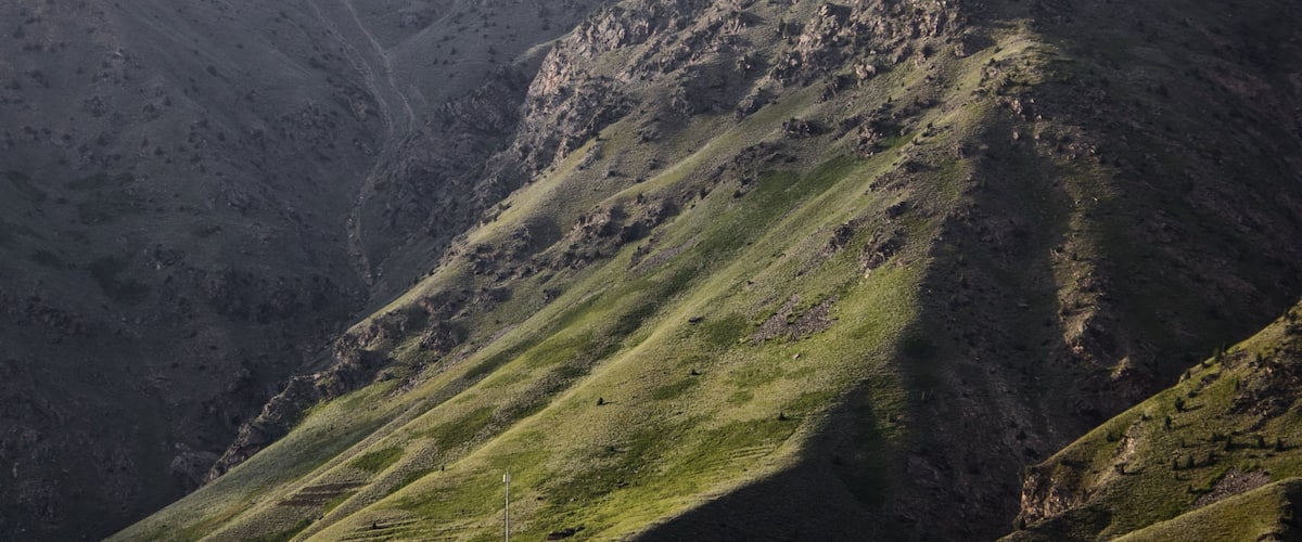 A rugged mountain landscape with steep slopes and sparse vegetation.