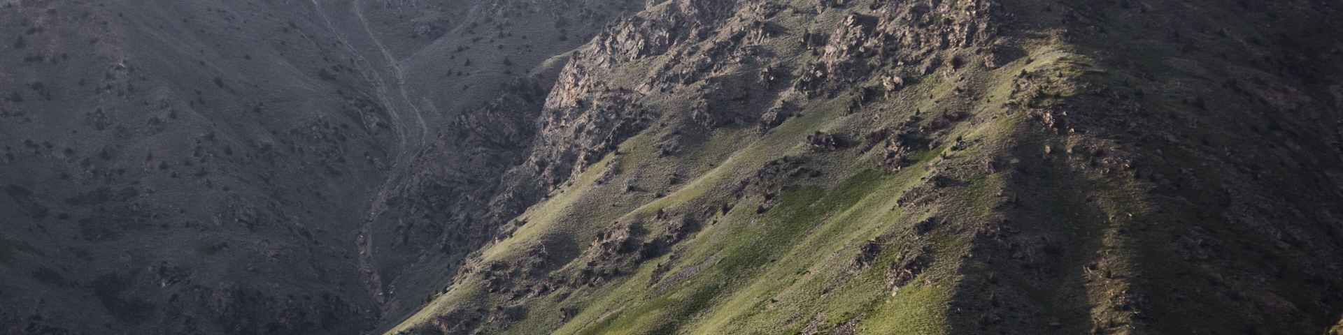 A rugged mountain landscape with steep slopes and sparse vegetation.