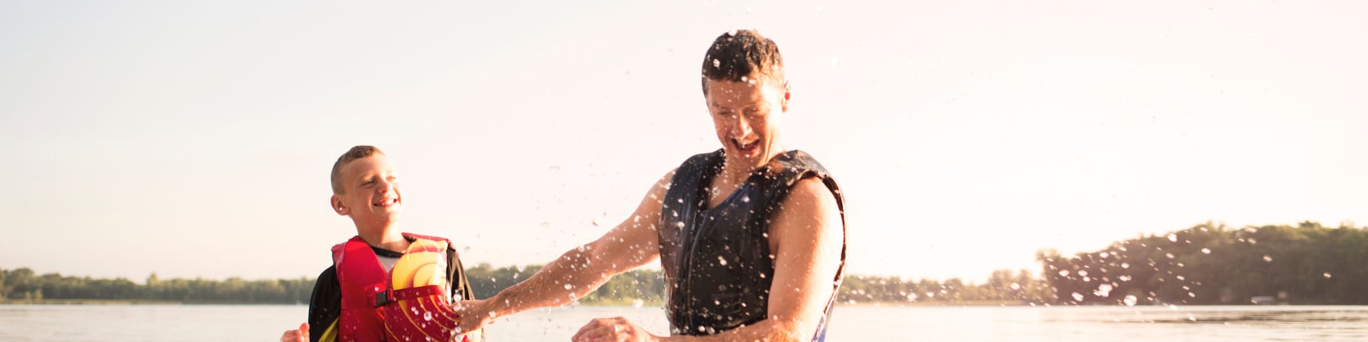 Deux personnes pratiquant un sport nautique, avec une étendue d’eau et une côte visible au loin.