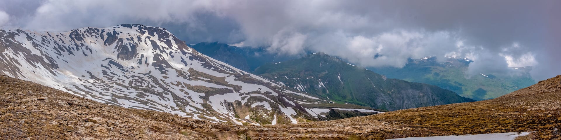 Panorama view of colorful mountains, meadow, and valley with clouds. Ski resort. Early morning, Sharr Mountains, Popova Shapka, North Macedonia.
