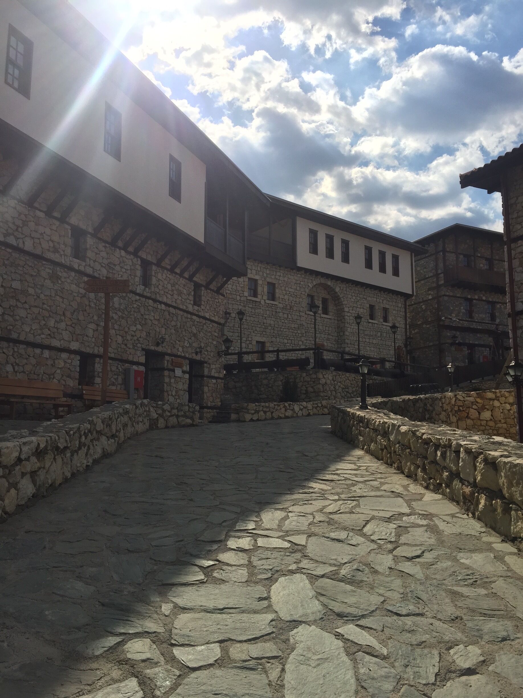 A courtyard with stone walls and a white building with multiple windows.