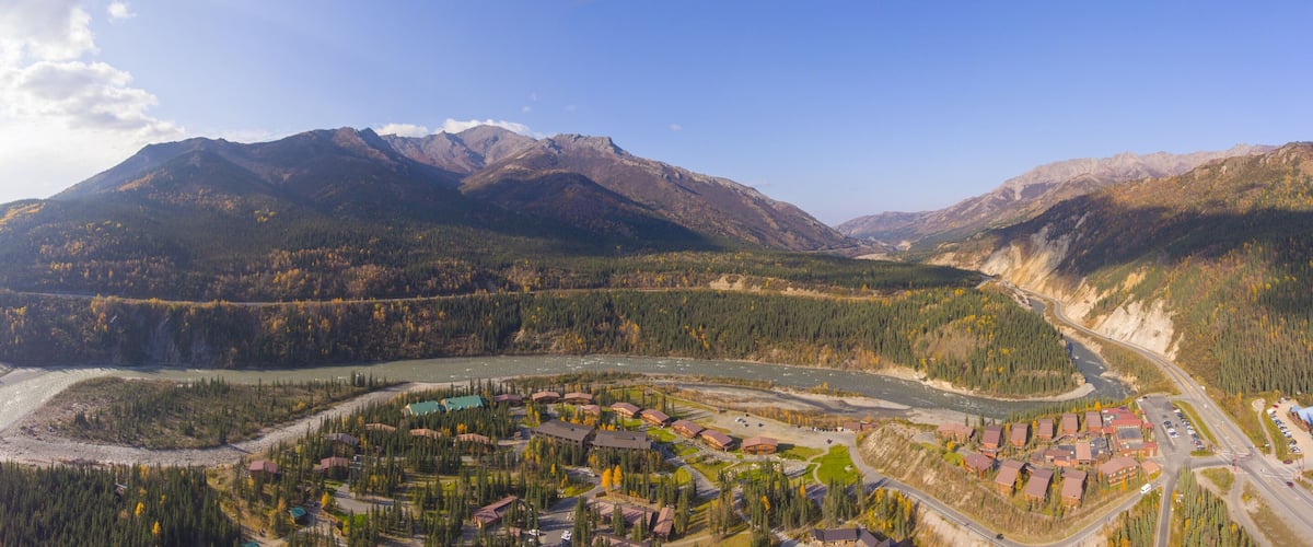 A river winding through a mountainous landscape with a small town and buildings along the riverbanks.