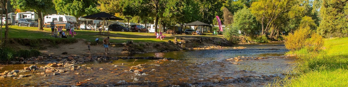 A river flowing through a campground with RVs and picnic tables.