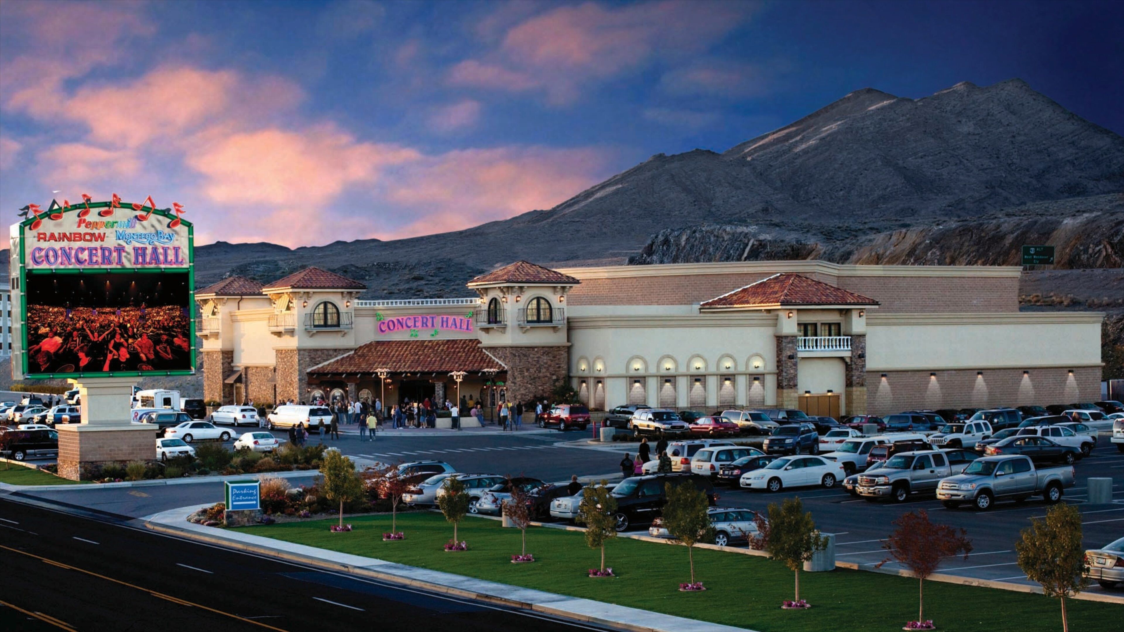 A concert hall with a sign reading "Rainbow Concert Hall" and a parking lot filled with cars.