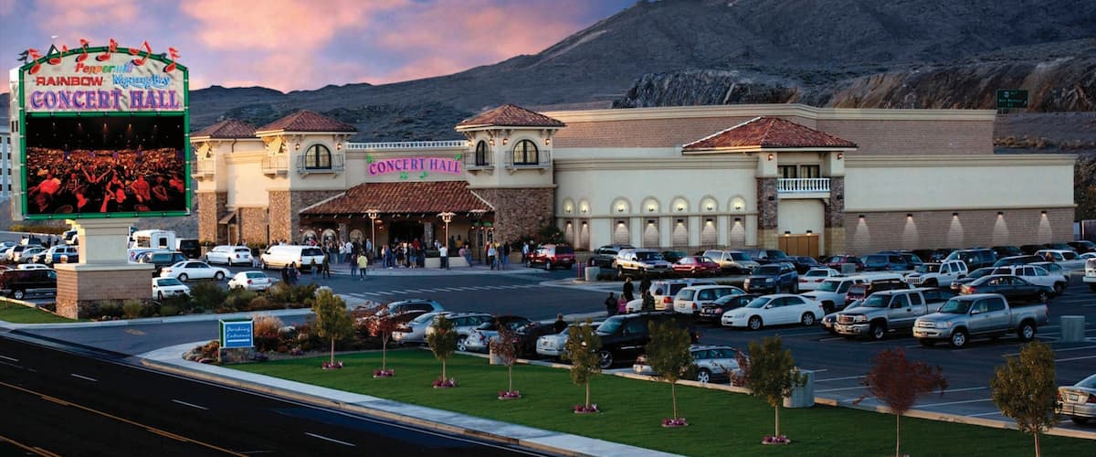A concert hall with a sign reading "Rainbow Concert Hall" and a parking lot filled with cars.