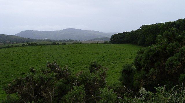 Farmland south of Ballagyr Lane. Somewhere in this area earthworks are shown on early maps as 'The Court'. I couldn't see any evidence in this field which is on the south side of the narrow Ballagyr Lane. The earthworks have probably been ploughed out. In the distance is Slieau Whallian (333m).