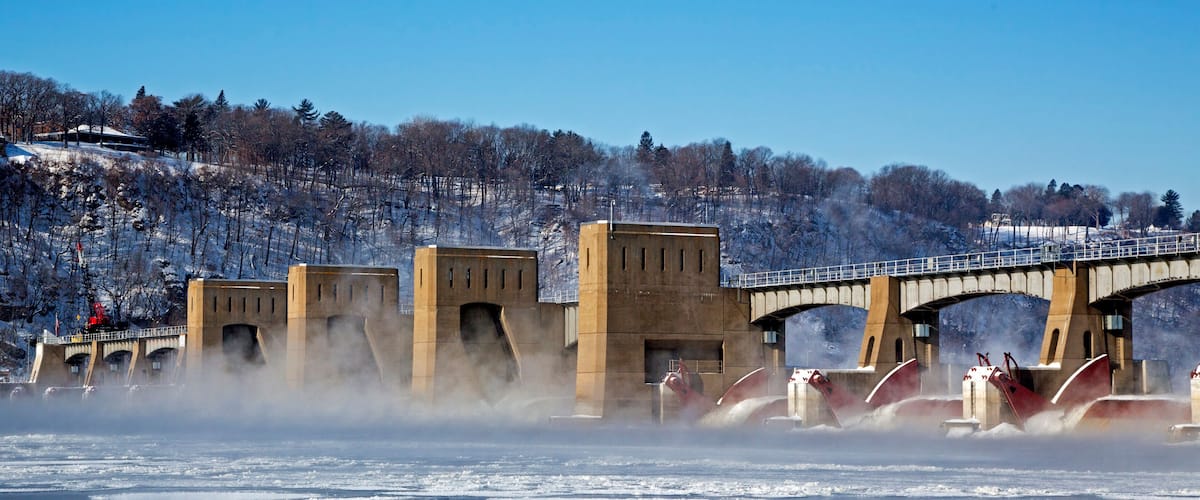 A frozen river with a bridge and snow-covered trees.
