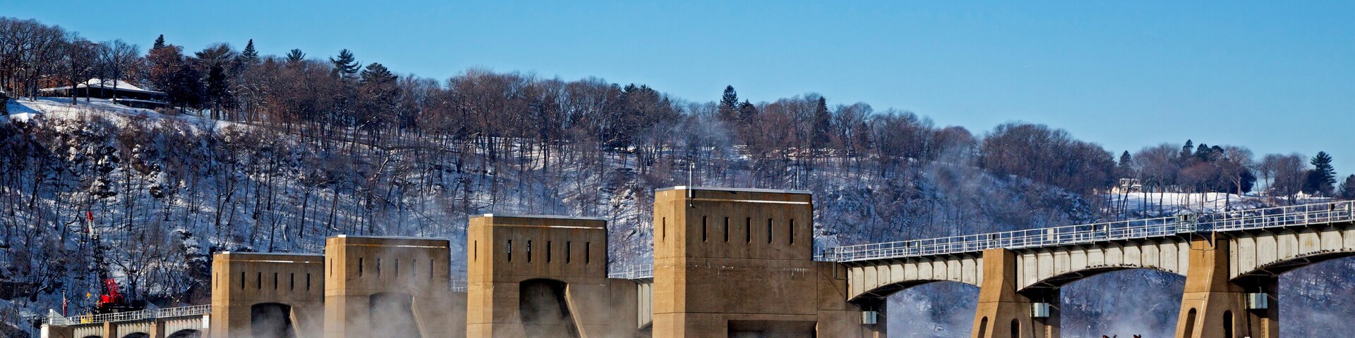 A frozen river with a bridge and snow-covered trees.